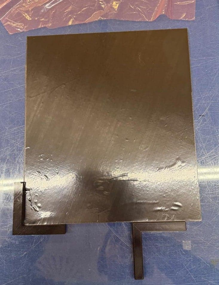 Cured composite panel on the bench with surface wrinkling visible across the plate