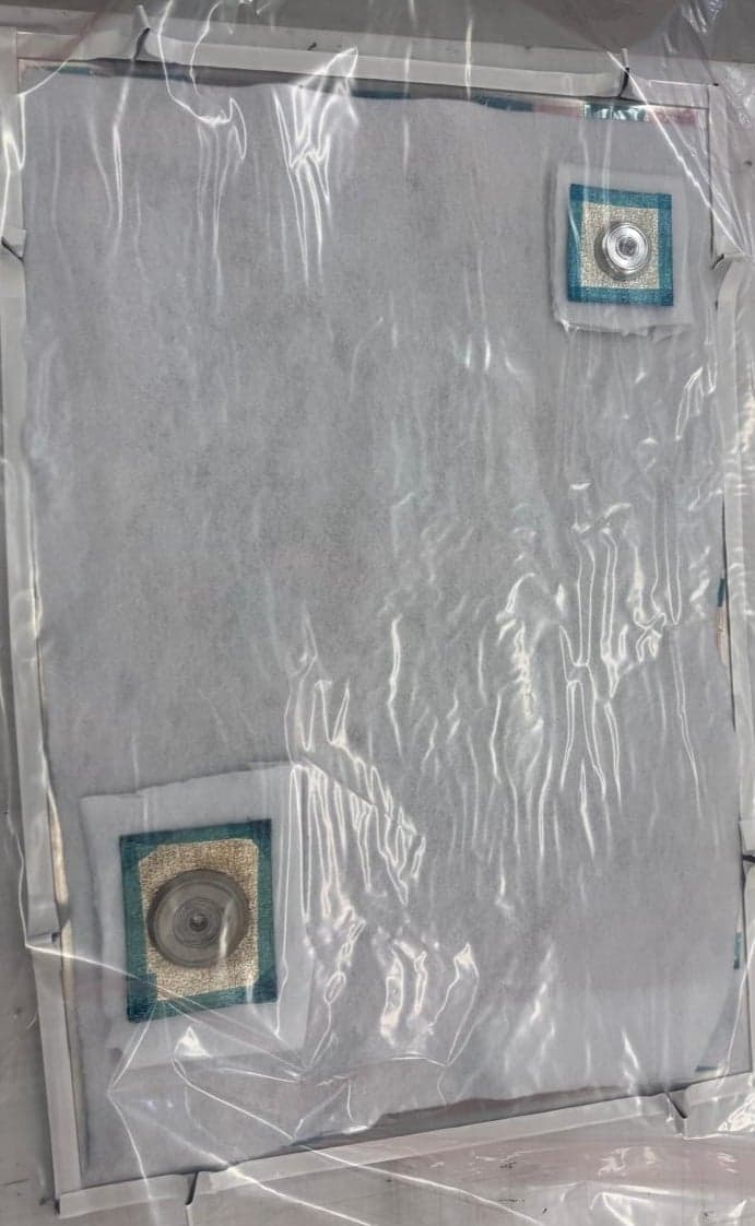 Composite panel sealed under a vacuum bag with breather and vacuum ports